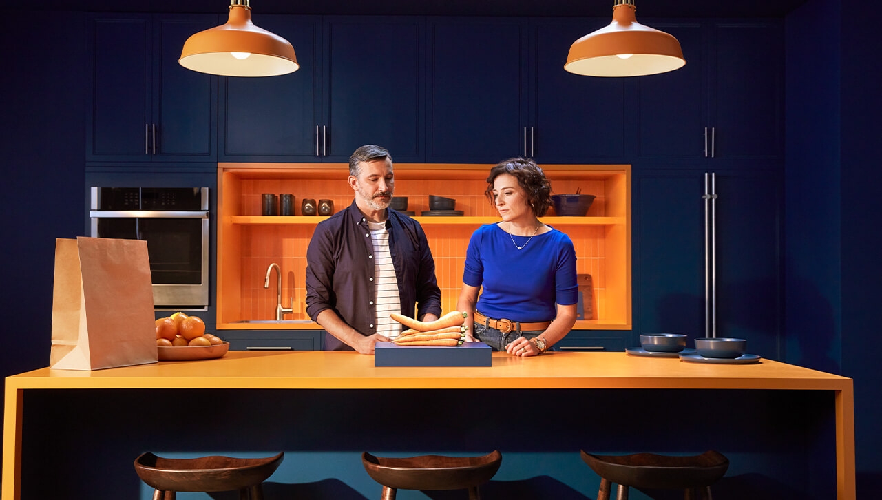 married couple in kitchen looking at bent carrot